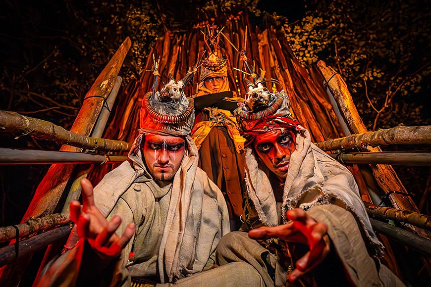 Live scare actors costumed as stylized cultists or tribal characters at a Halloween event