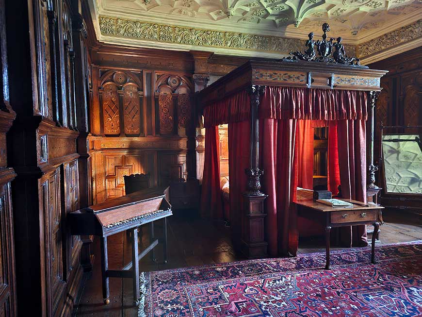 The Inlaid Chamber with four-poster bed and red drapes, with Elizabethan joinery, ornate plasterwork and elaborate inlaid panelling