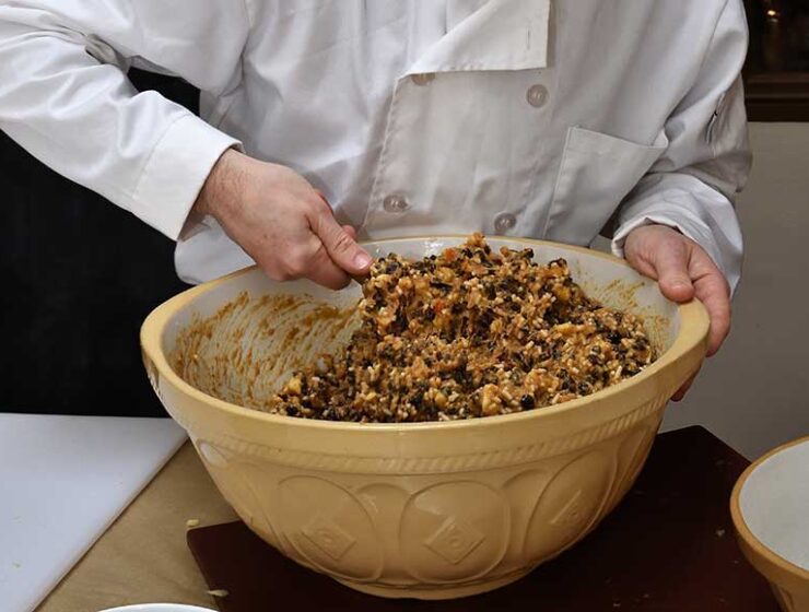 Close up of chef stirring the Christmas pudding mixture in a large yellow china bowl