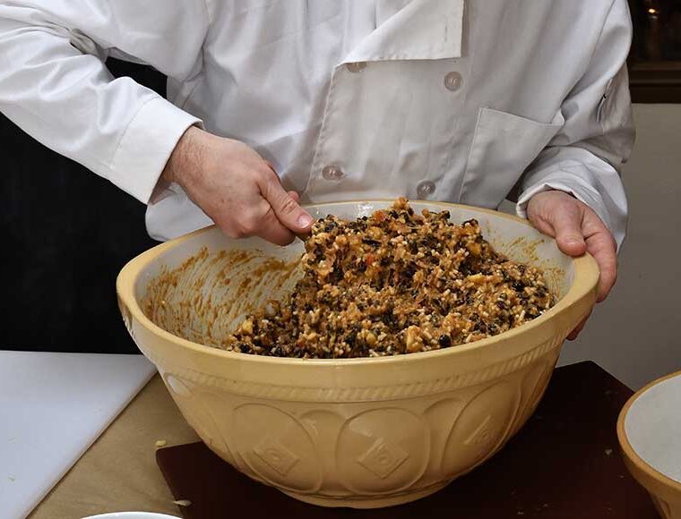 Close up of chef stirring the Christmas pudding mixture in a large yellow china bowl
