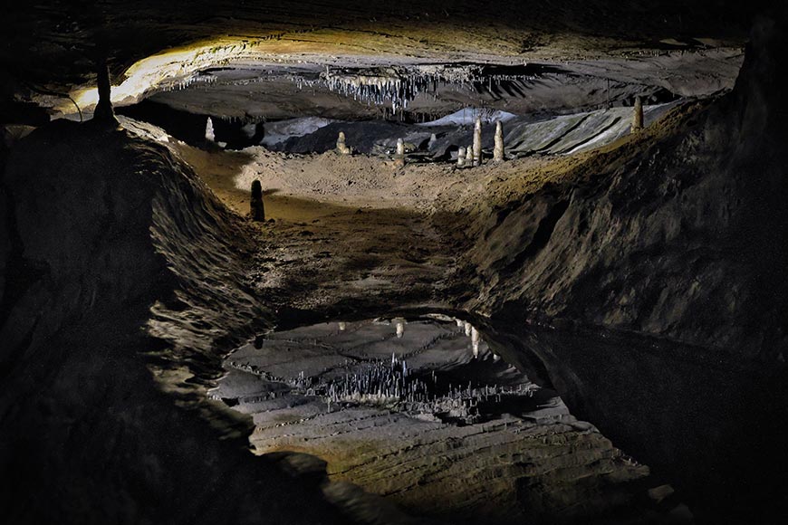 Stalagmites and stalactites reflected in a pool giving illusion of a cityscape at Ingleborough Cave Yorkshire UK