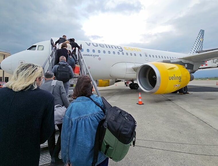 Passengers with hand luggage climbing the steps to board Airbus A319