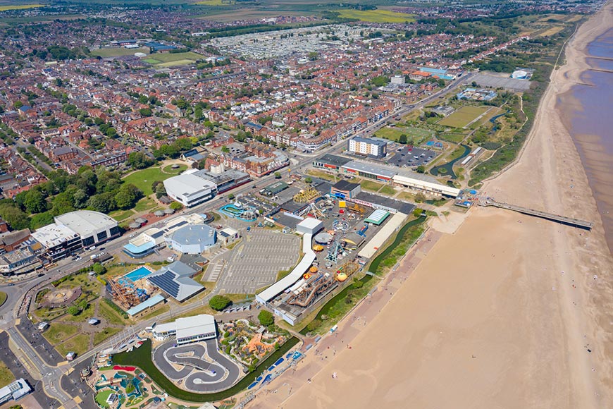 Aerial photo of the town centre of Skegness showing the pier on the sandy beach near fairground rides in the East Lindsey district of Lincolnshire, England