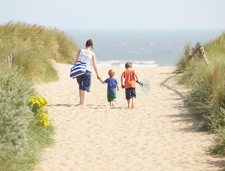 Female and two children walking on the sand on Mablethorpe beach