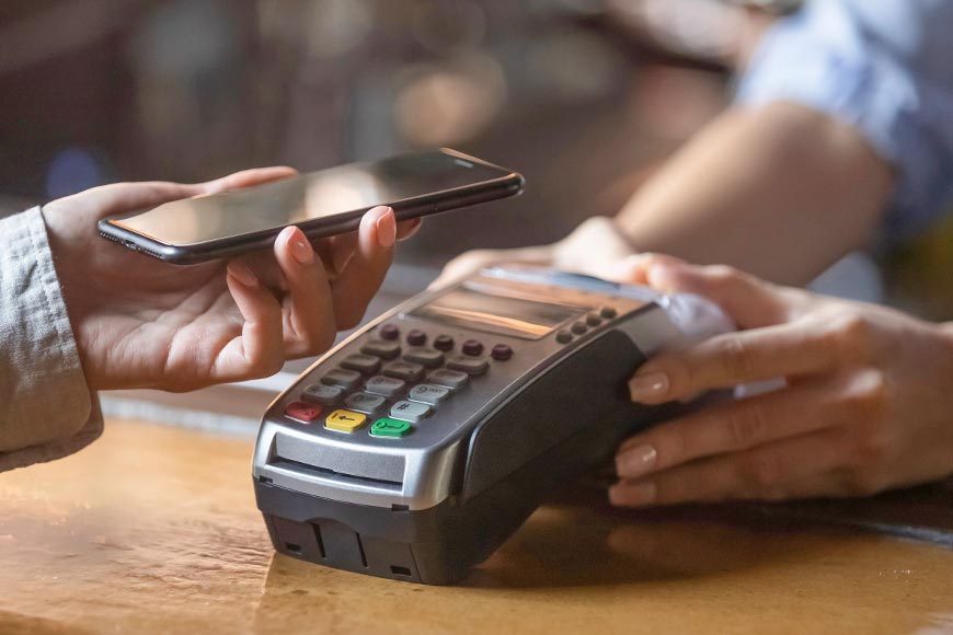 Close up of female client hold smartphone paying for order using modern easy nfc technology, waiter give card reader machine for customer make payment transaction with cashless contactless method